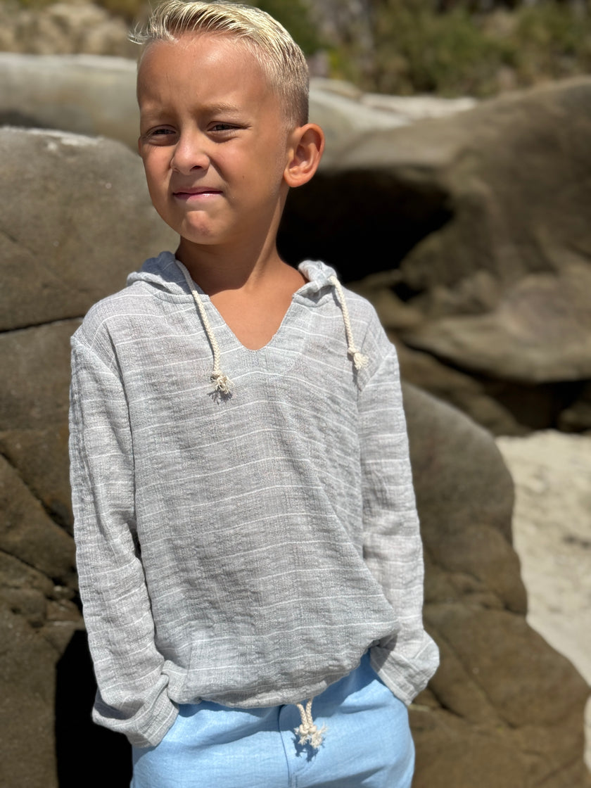 Child wearing a gray hoodie and blue pants standing on rocky terrain