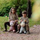Two children sitting on inflatable animal toys in a park
