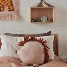 Children's room with lion-shaped pillow, wall shelf, and decorative items.