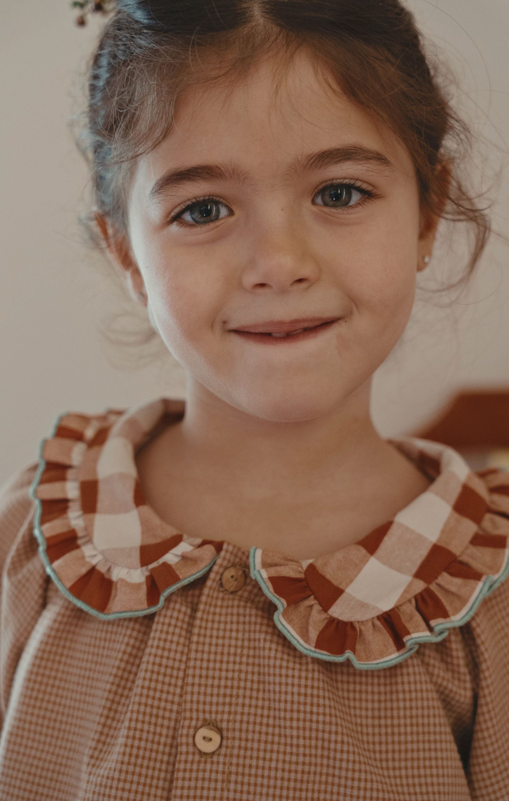 A young girl button-up shirt with a ruffled collar in brown, beige