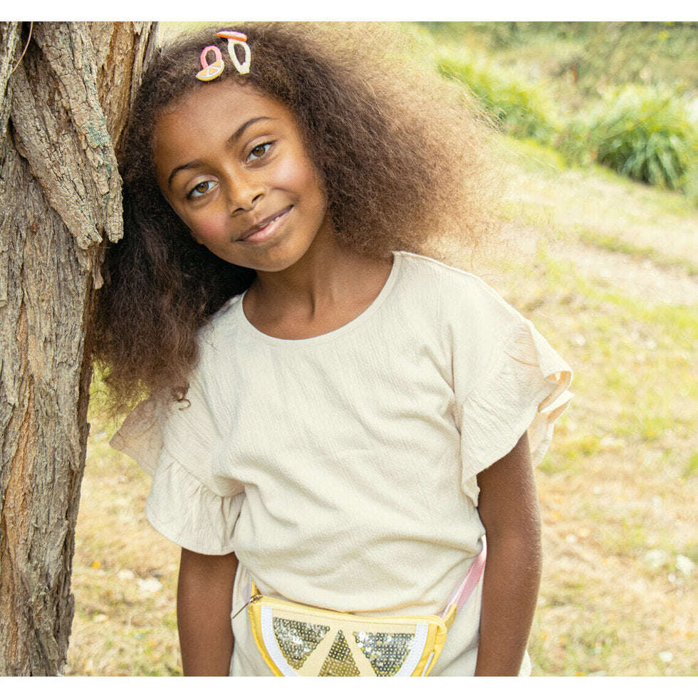 Young girl with curly hair leaning against a tree outdoors