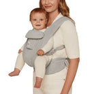 Woman carrying a baby in a gray baby carrier on a white background