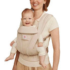Woman carrying a baby in a beige baby carrier.