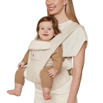Woman carrying a baby in a beige baby carrier.