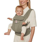 Woman carrying a baby in a green baby carrier.