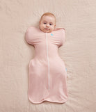 Baby wrapped in a pink sleeping bag on a soft beige surface
