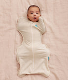 Baby wrapped in a cream-colored swaddle on a pink blanket
