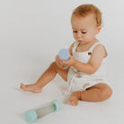 Baby sitting on a white surface holding a blue toy