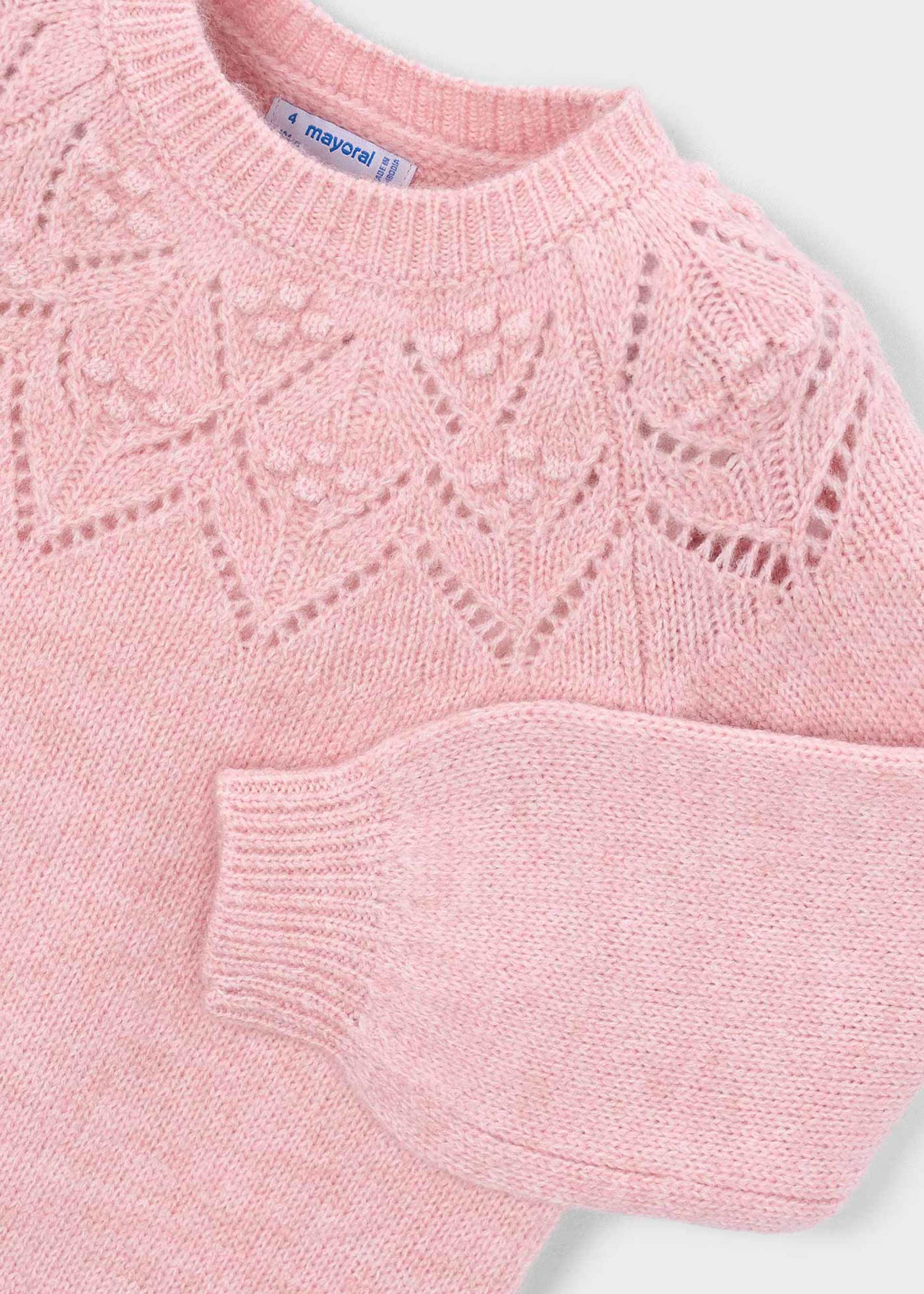 A close-up of a light pink knit sweater with a textured geometric lace pattern across the chest and a ribbed crew neck, sleeve, and cuffs. The brand label 'mayoral' is visible inside the collar.