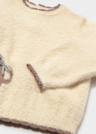 Close-up of a beige knitted sweater with brown accents on a white background