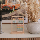 Colorful abacus on a shelf with a vase of dried flowers and a vintage car photo in the background.