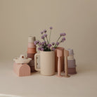 Collection of ceramic items including vases, a mug, and a candle holder on a neutral background