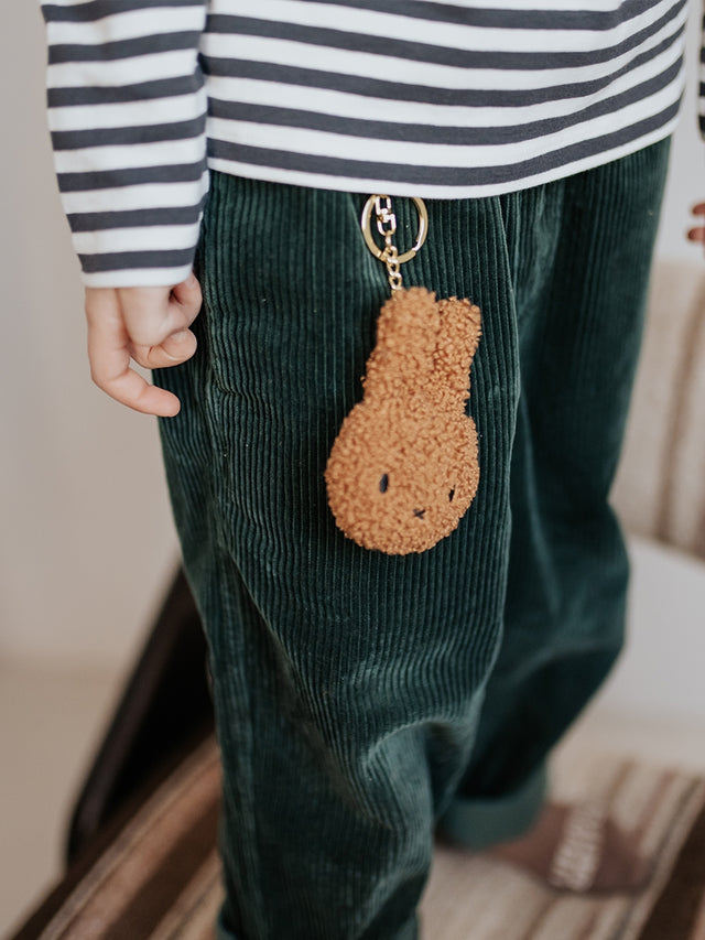 Person wearing green pants with a brown keychain attached, striped shirt visible