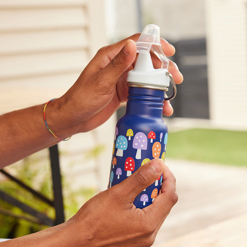 Person holding a blue water bottle with mushroom pattern outdoors