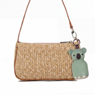 Woven handbag with a koala keychain on a white background