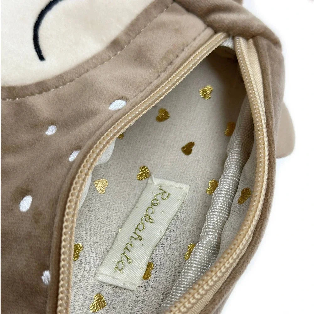 Close-up of a baby shoe with gold polka dots and a brand label on a white background