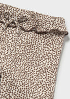 Leopard print pants with ruffled waistband on a light gray background