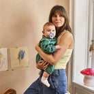 Baby with a blue pacifier wearing a green shirt