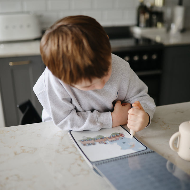 Child sitting at a kitchen counter with a coloring book and crayon
