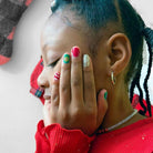 Person with colorful nail polish and red sweater covering face