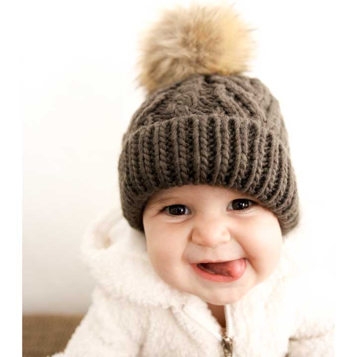 Child wearing a brown knitted hat with a pom-pom on a white background