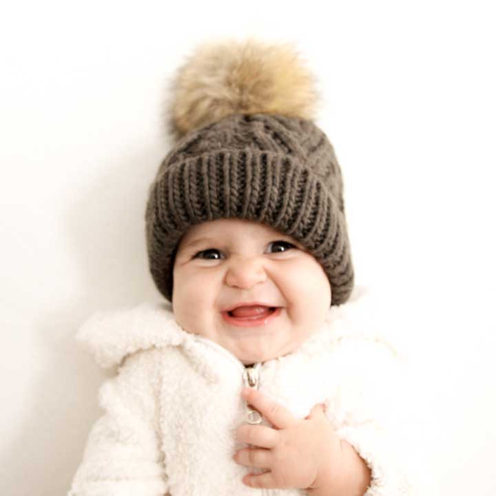 Baby wearing a knitted hat with a pom-pom on a white background