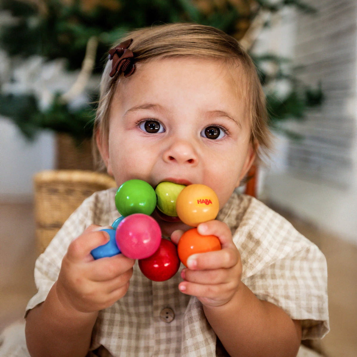 Child holding a colorful baby teether with a blurred indoor background