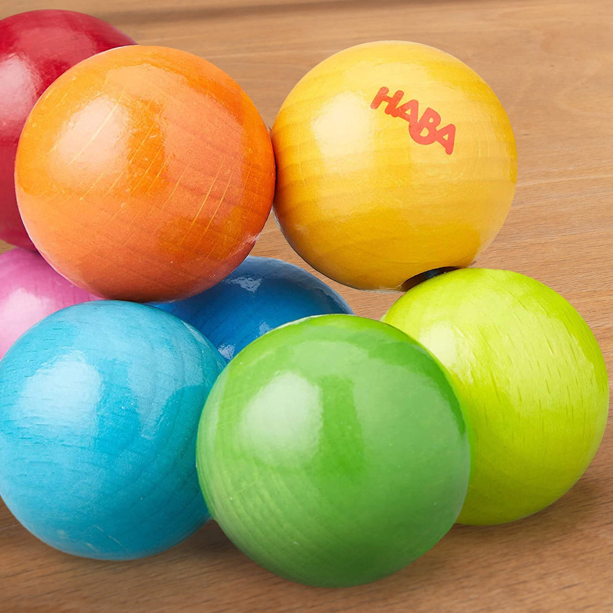 Colorful wooden balls with 'HABA' branding on a wooden surface