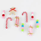 A set of Christmas-themed hair clips arranged on a plain white background, including candy cane, gingerbread man, striped candy, and pom-pom designs in red, white, pink, green, blue, and gold.