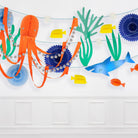 Colorful paper decorations of an octopus, fish, and plants on a white wall.
