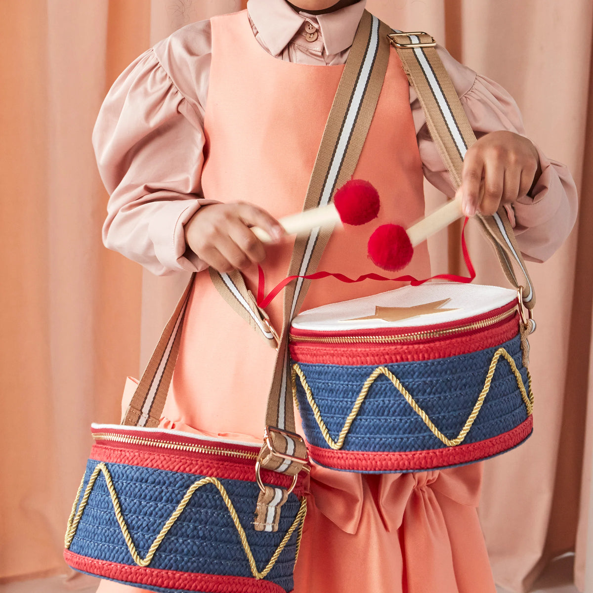 Meri Meri Drum Bag, featuring a festive blue and red woven design with gold zigzag detailing and playful pompom drumsticks