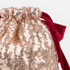 Close-up of a gold sequin bag with a red ribbon on a white background