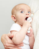 Baby holding a white toy with a neutral background