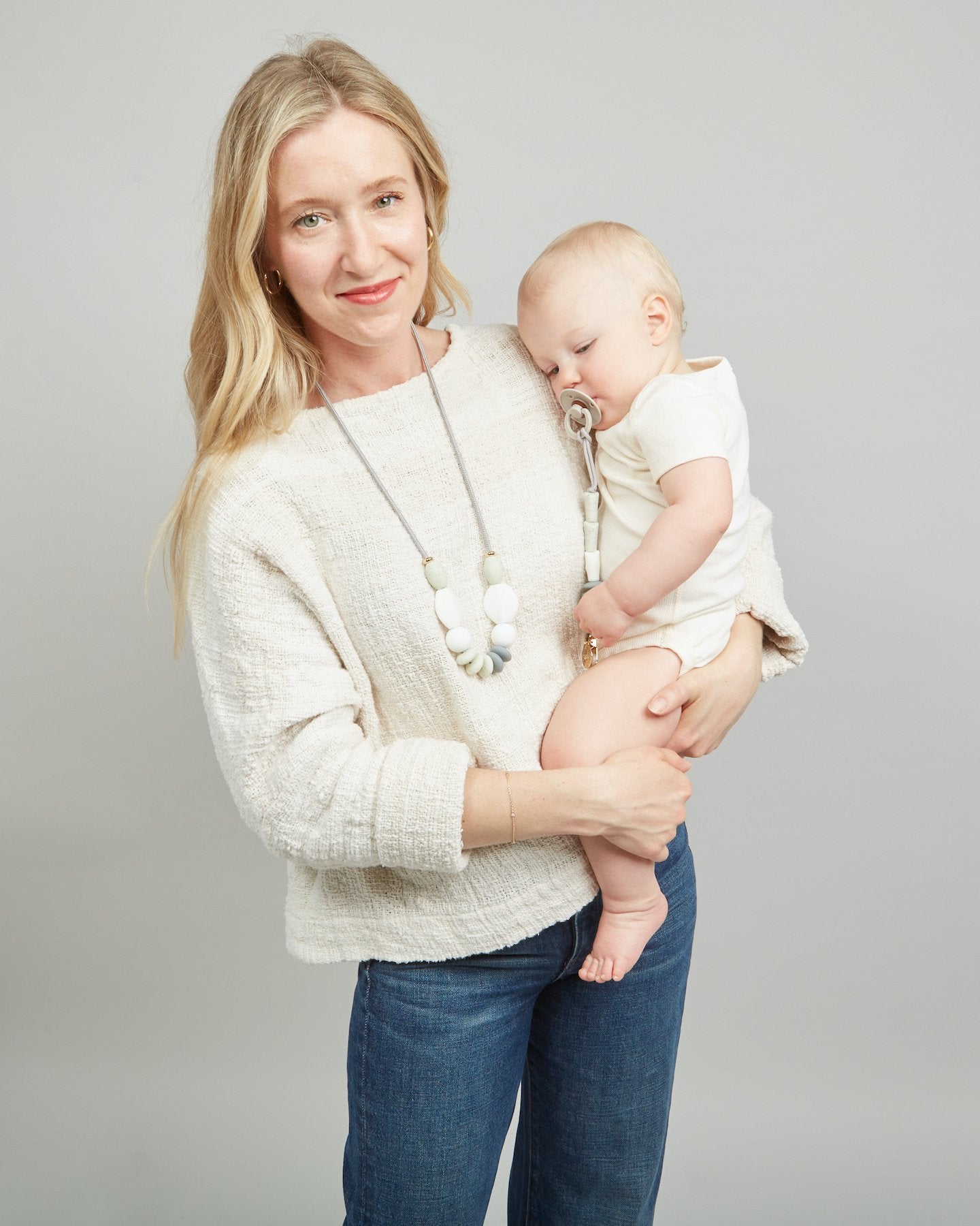 Woman holding a baby against a plain background