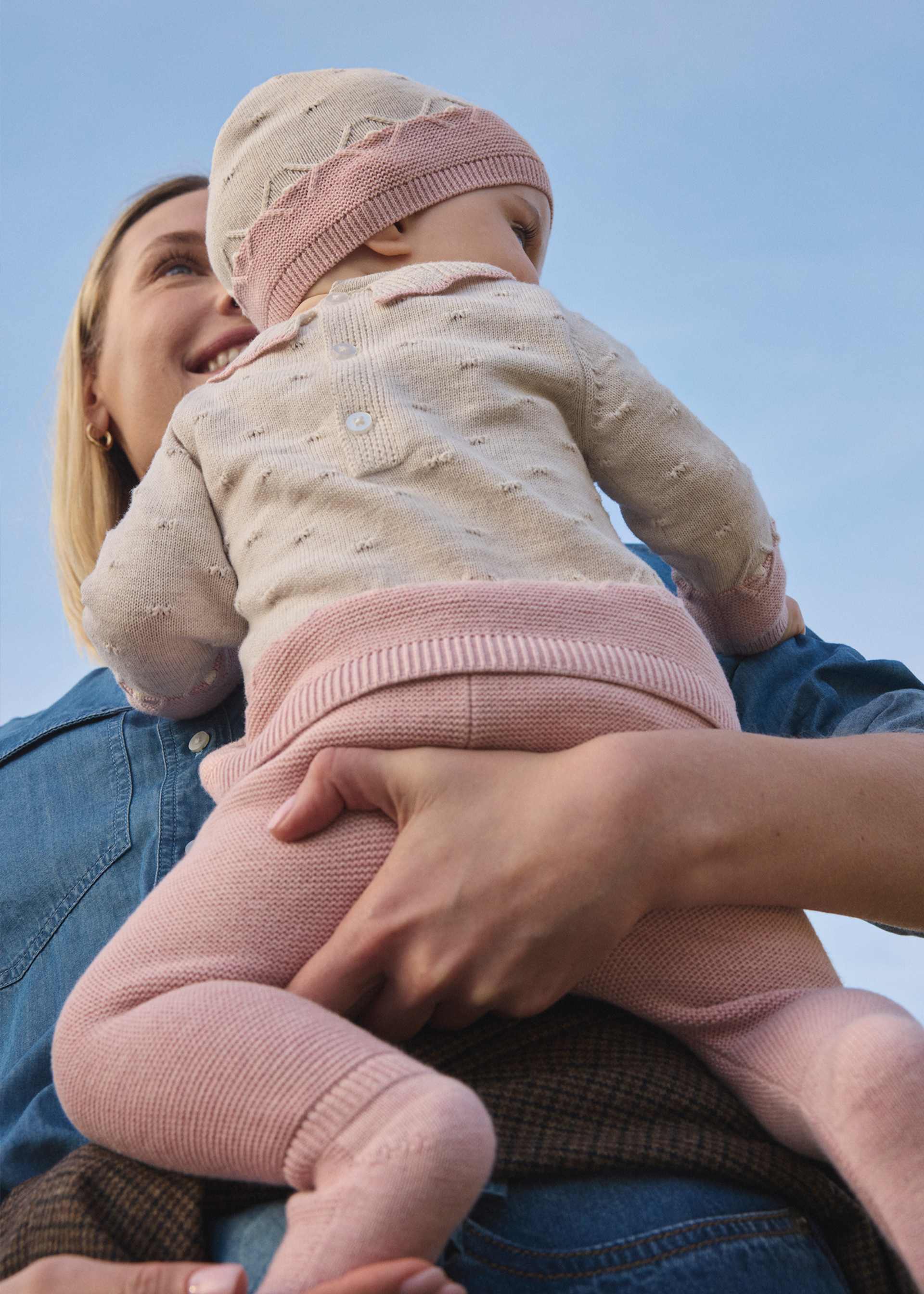 Woman holding a baby against a clear blue sky