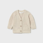 A cream-colored knit cardigan sweater for toddlers, featuring a V-neck, three wooden buttons, raglan sleeves, and a front patch pocket, shown on a light gray background.