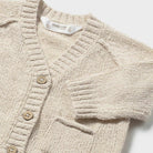 Beige knitted cardigan with button details on a white background