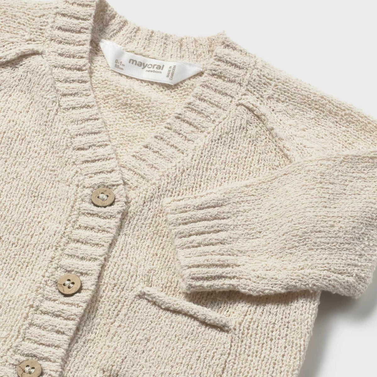 Beige knitted cardigan with button details on a white background