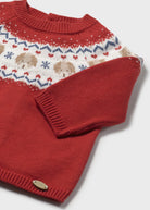 Red knitted sweater with a pattern on a white background