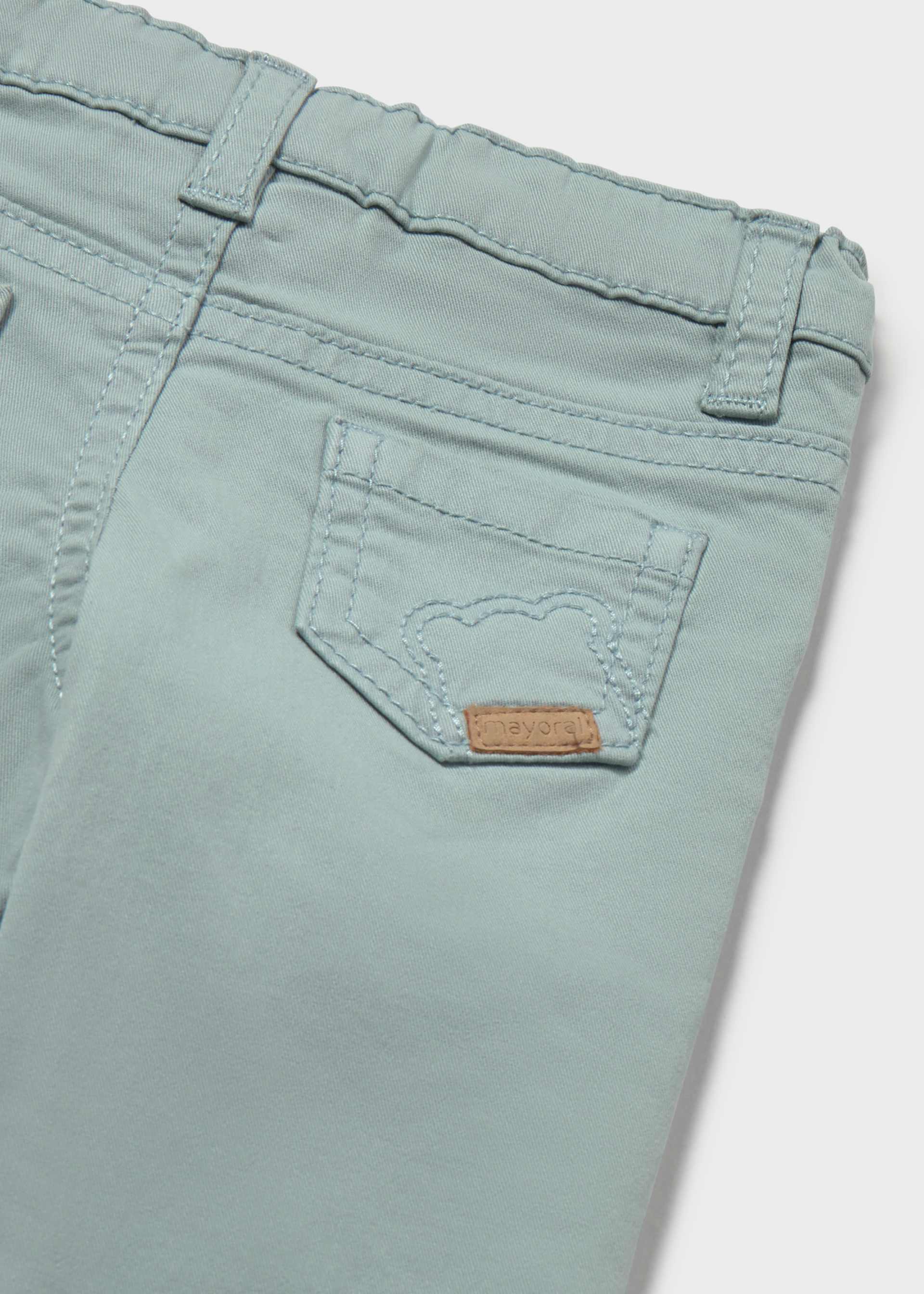 Close-up of a pair of light mint green denim jeans showing the back pocket with a small brown leather brand patch.