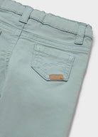 Close-up of a pair of light mint green denim jeans showing the back pocket with a small brown leather brand patch.