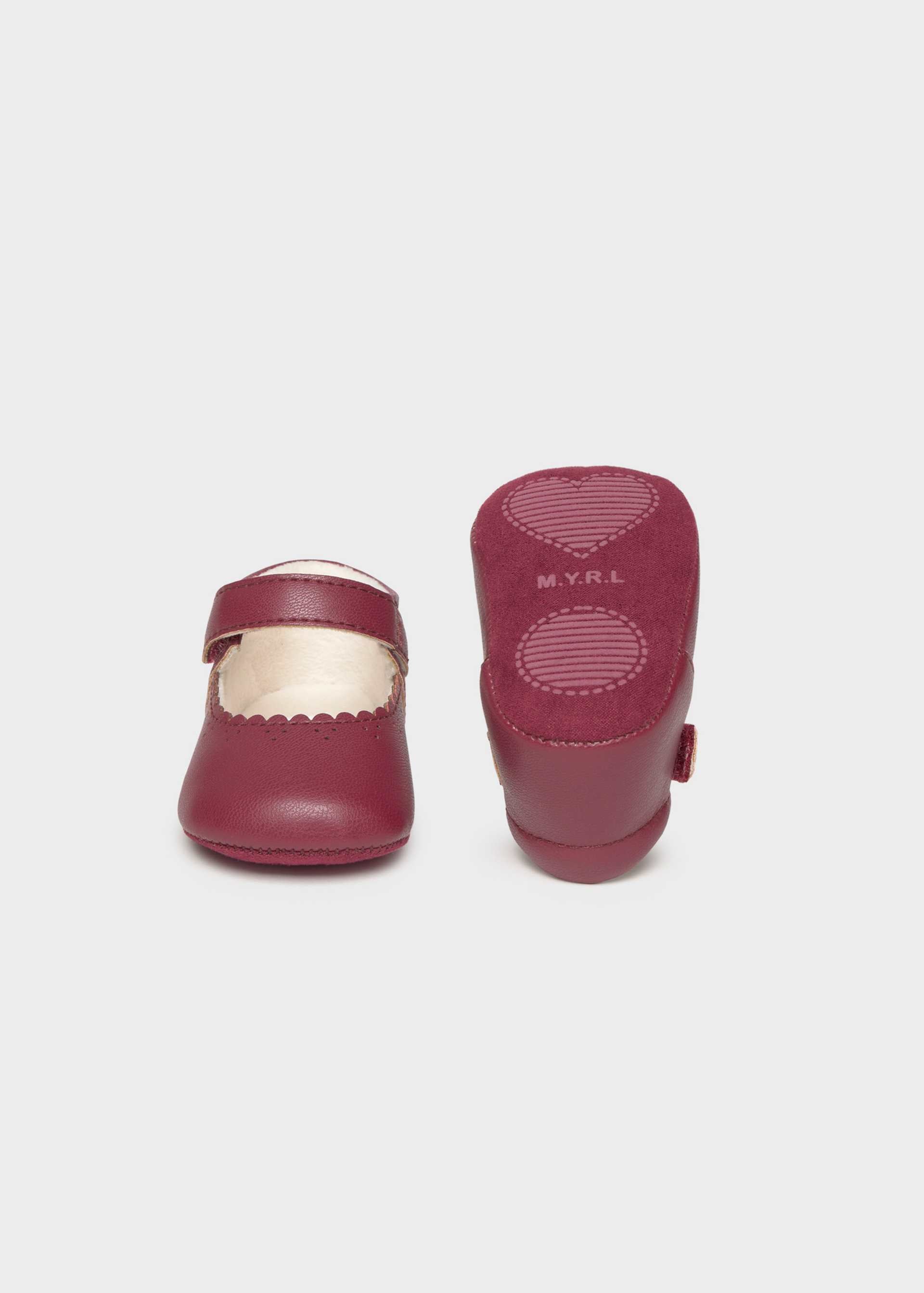 Pair of maroon children's shoes on a light gray background