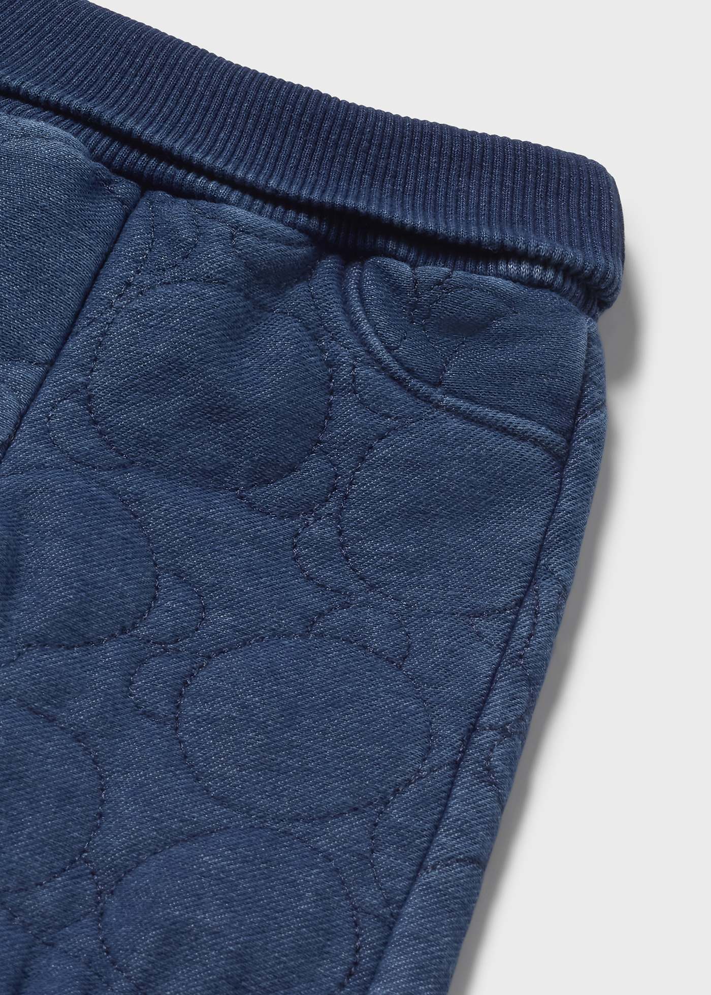 Close-up of blue textured fabric with a pattern on a light gray background