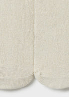 Close-up of a pair of off-white knit socks showing the ribbed texture and toe seams.