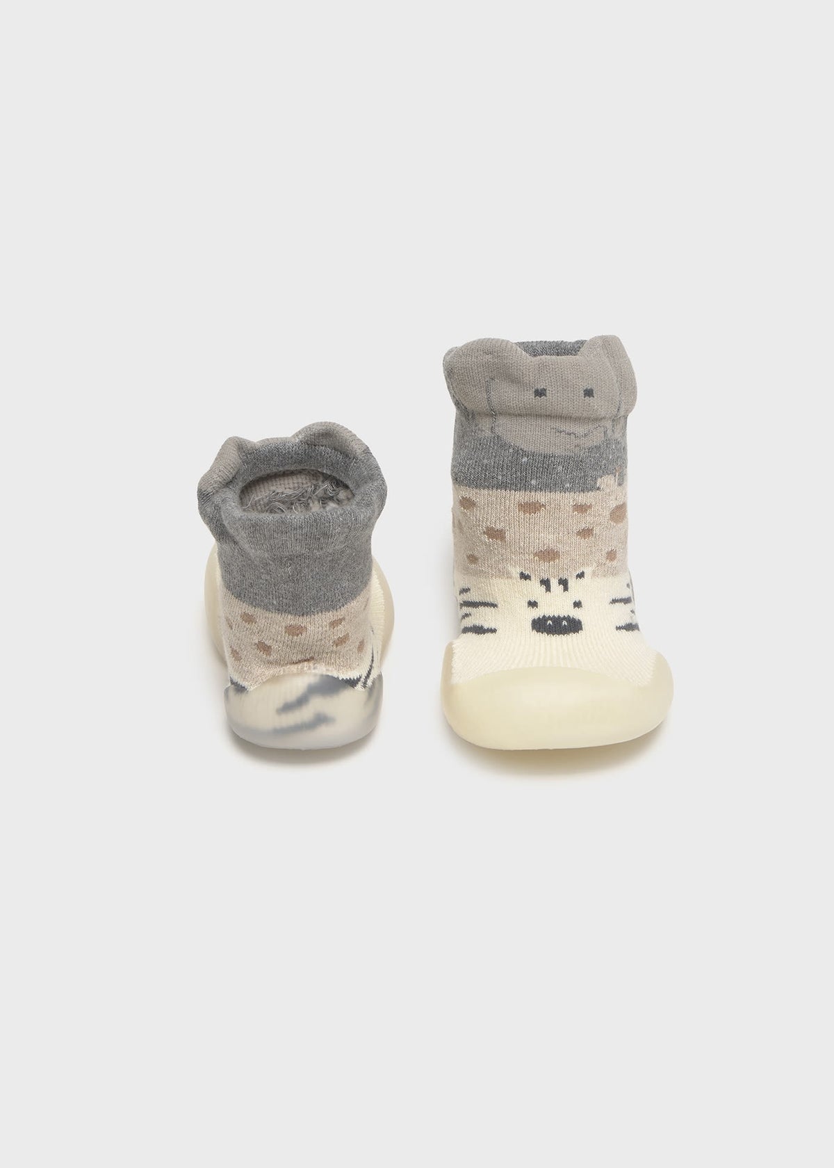 Pair of baby shoes with gray tops and white soles on a light gray background