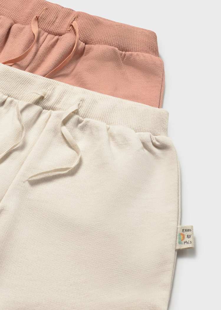 Two pairs of pants, one pink and one beige, on a light gray background.