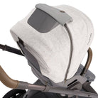 A close-up of a stroller canopy cover in light heather gray fabric with darker gray trim, shown attached to a stroller frame against a white background.