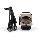 A Cybex stroller and infant car seat travel system shown on a clean white background. The stroller is folded on the left in black, and the infant car seat with a beige/tan hood and harness base is shown on the right.
