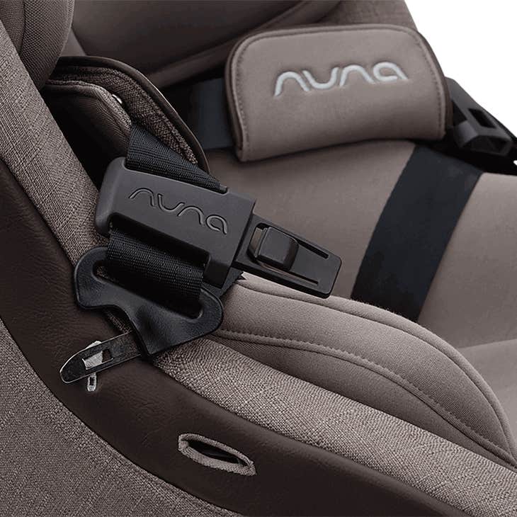 Close-up of a Nuna car seat with a focus on the buckle and logo.