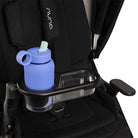 A light blue silicone water bottle with a mint green straw, held in a black and clear stroller cup holder attached to a black stroller seat.